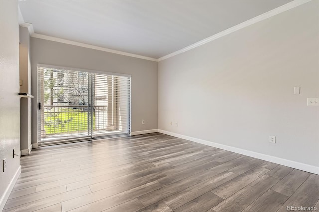 spare room with wood finished floors, crown molding, and baseboards