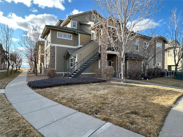 view of front of house with stairs, central AC unit, and a front yard