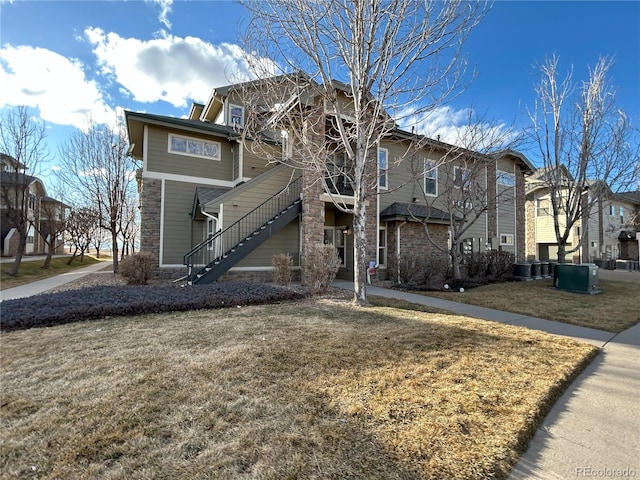 view of front of house featuring a front lawn, stairway, and cooling unit