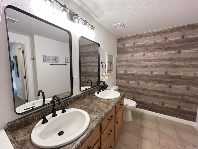 full bath featuring visible vents, a sink, wooden walls, and a textured ceiling