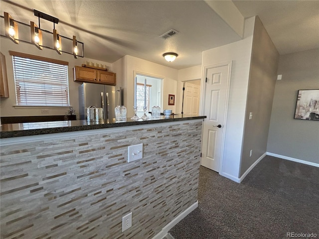 kitchen featuring baseboards, visible vents, freestanding refrigerator, dark colored carpet, and a wealth of natural light