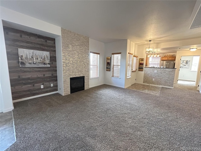 unfurnished living room featuring wood walls, carpet, a fireplace, and an accent wall