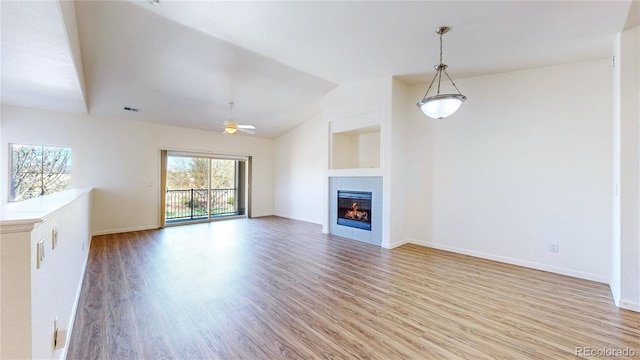 11374 Xavier Dr Unit 202, Westminster, CO 80031 - unfurnished living room with light wood-style floors, a tiled fireplace, lofted ceiling, a ceiling fan, and baseboards