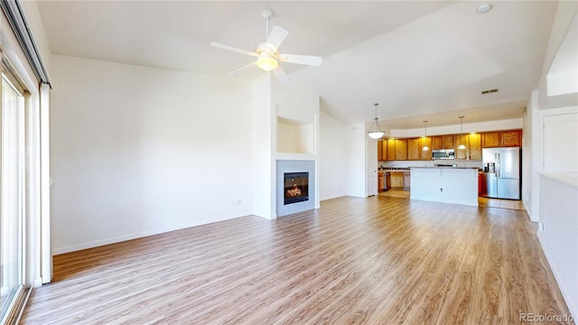 11374 Xavier Dr Unit 202, Westminster, CO 80031 - unfurnished living room featuring light wood-style floors, ceiling fan, a glass covered fireplace, baseboards, and high vaulted ceiling