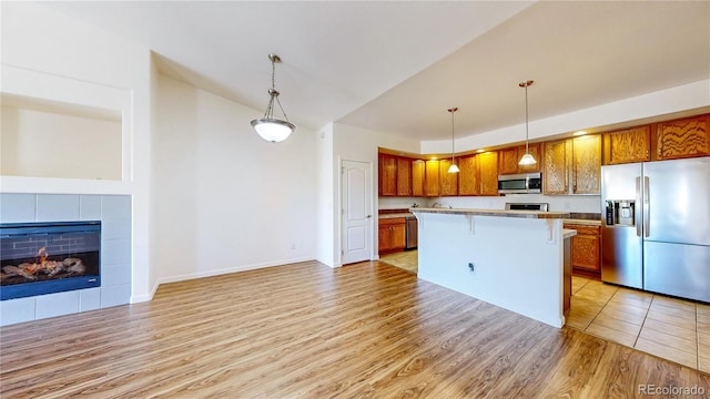 11374 Xavier Dr Unit 202, Westminster, CO 80031 - kitchen featuring stainless steel appliances, light wood finished floors, brown cabinets, and decorative light fixtures