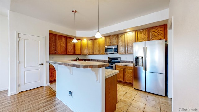 11374 Xavier Dr Unit 202, Westminster, CO 80031 - kitchen featuring appliances with stainless steel finishes, a kitchen breakfast bar, brown cabinetry, decorative light fixtures, and a kitchen island