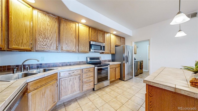 11374 Xavier Dr Unit 202, Westminster, CO 80031 - kitchen with stainless steel appliances, a sink, pendant lighting, light tile patterned floors, and tile countertops