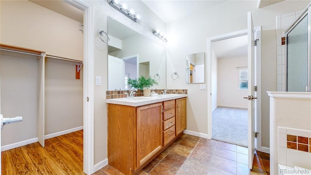 11374 Xavier Dr Unit 202, Westminster, CO 80031 - bathroom with double vanity, a shower with door, a walk in closet, baseboards, and backsplash