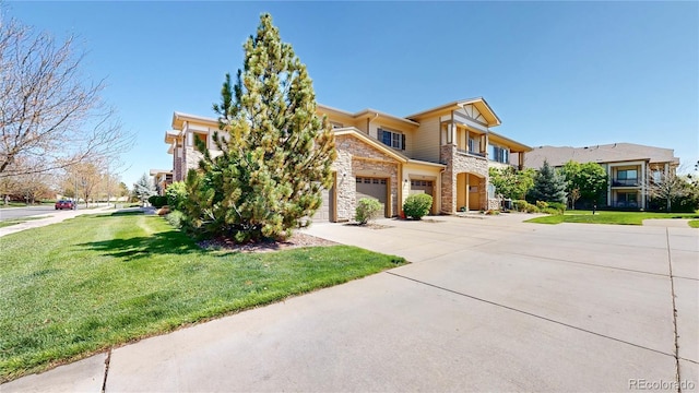 11374 Xavier Dr Unit 202, Westminster, CO 80031 - view of front facade with concrete driveway, a garage, stone siding, and a front lawn
