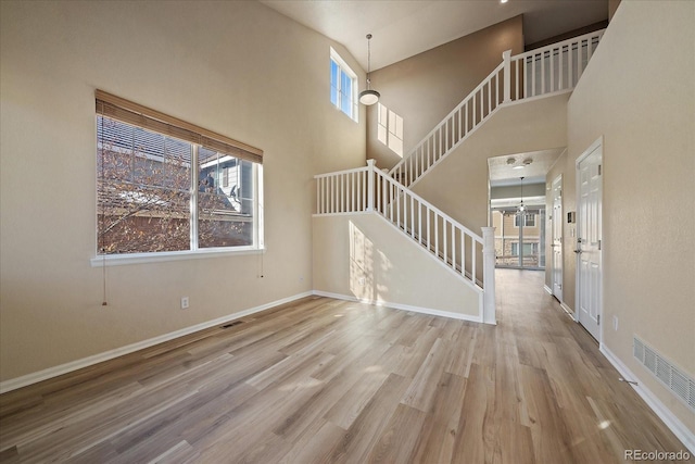 foyer entrance with light hardwood / wood-style floors and a towering ceiling