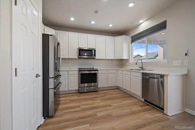 kitchen featuring sink, white cabinets, light hardwood / wood-style floors, and appliances with stainless steel finishes