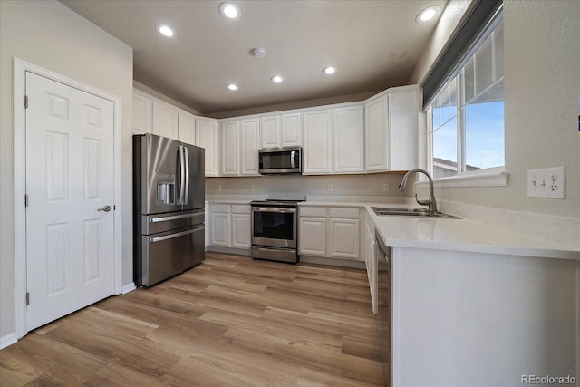 kitchen with white cabinetry, stainless steel appliances, light hardwood / wood-style floors, sink, and light stone counters