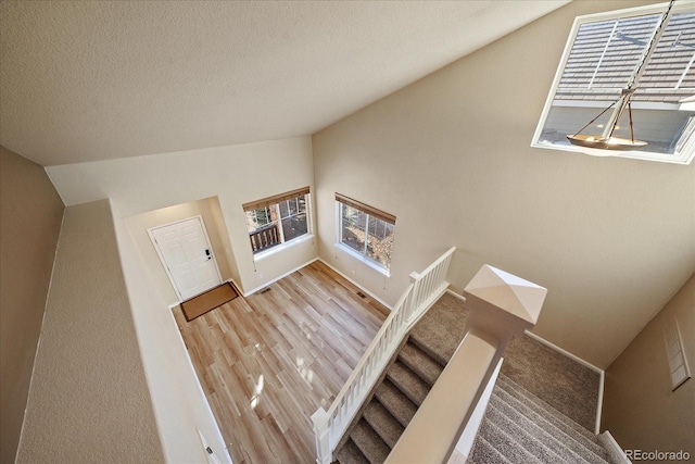 stairway with a healthy amount of sunlight and vaulted ceiling