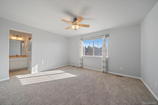 unfurnished bedroom featuring sink, ceiling fan, light carpet, and ensuite bath