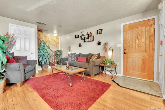 living room with brick wall, wood-type flooring, and a textured ceiling