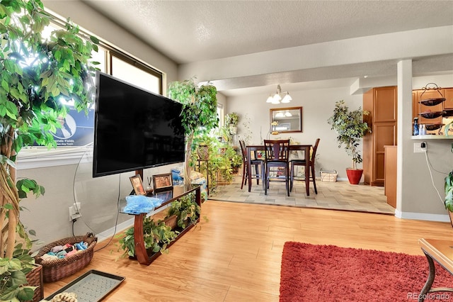 living room with light hardwood / wood-style flooring, a notable chandelier, and a textured ceiling