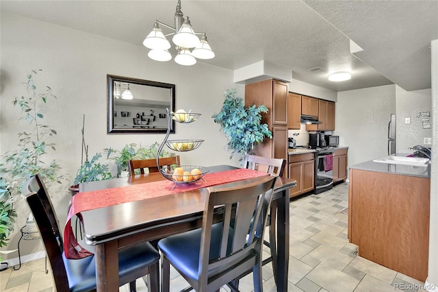 dining space featuring a notable chandelier, a textured ceiling, and sink