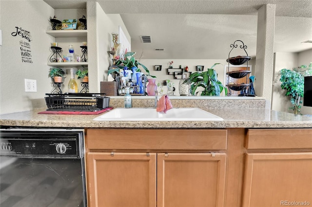 kitchen featuring light brown cabinetry, sink, dishwasher, and a textured ceiling