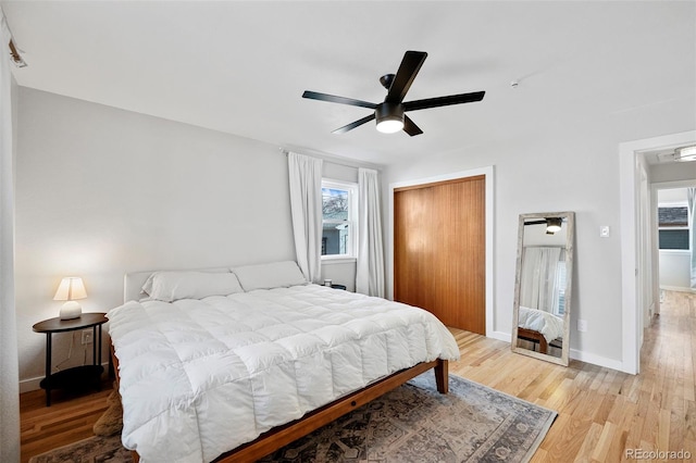 bedroom with ceiling fan, light hardwood / wood-style floors, and a closet