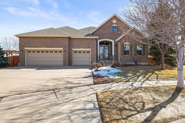 traditional-style home with driveway, a shingled roof, an attached garage, fence, and brick siding