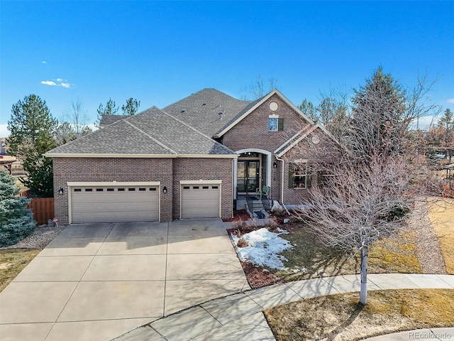 traditional-style house with a garage, concrete driveway, brick siding, and a shingled roof