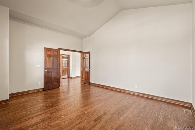 empty room featuring dark wood-style floors, baseboards, visible vents, and high vaulted ceiling