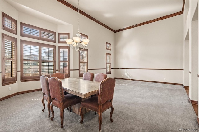 carpeted dining space with baseboards, a notable chandelier, and ornamental molding