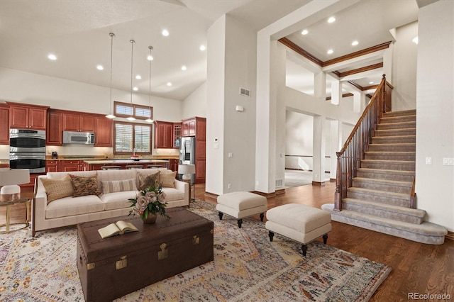 living room with recessed lighting, visible vents, stairway, a towering ceiling, and light wood-type flooring