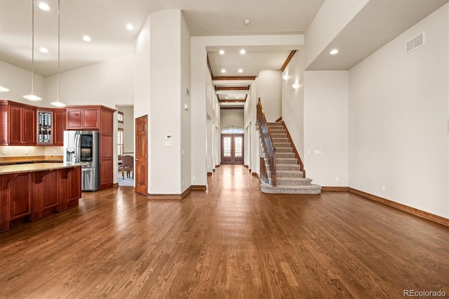 interior space featuring dark wood-type flooring, visible vents, stairway, and baseboards