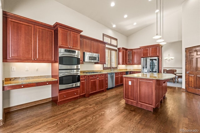 kitchen with dark wood-style floors, hanging light fixtures, appliances with stainless steel finishes, glass insert cabinets, and a kitchen island