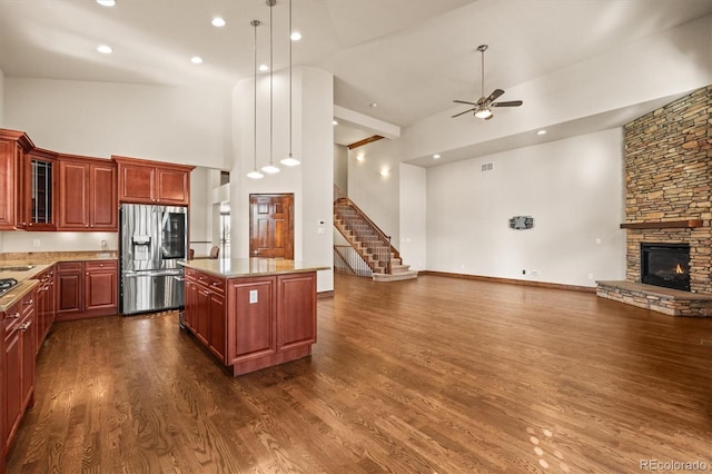 kitchen featuring open floor plan, dark wood-type flooring, a center island, a fireplace, and stainless steel refrigerator with ice dispenser