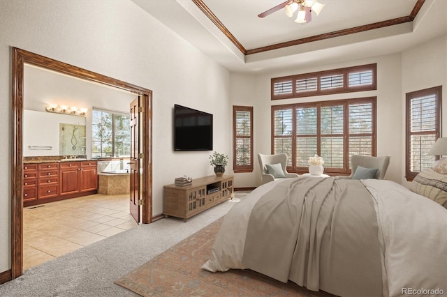 bedroom featuring light tile patterned flooring, connected bathroom, light carpet, ornamental molding, and a raised ceiling