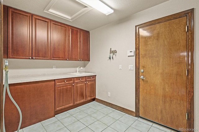 kitchen featuring light tile patterned floors, a sink, tile counters, and baseboards