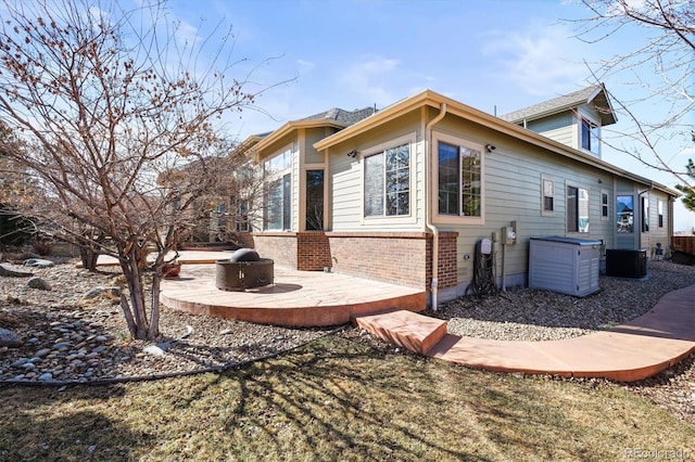 rear view of house featuring brick siding, a patio, and central air condition unit