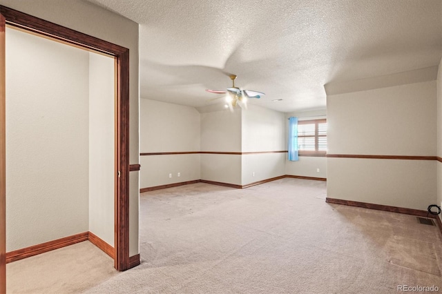 carpeted empty room with visible vents, ceiling fan, a textured ceiling, and baseboards