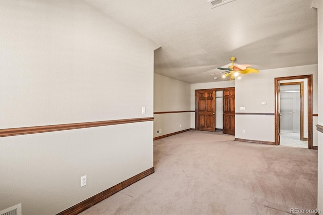 empty room with light carpet, baseboards, visible vents, a ceiling fan, and a textured ceiling