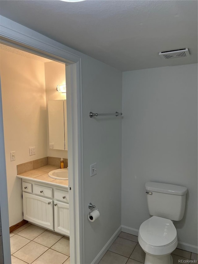 bathroom featuring tile patterned flooring, vanity, baseboards, and toilet