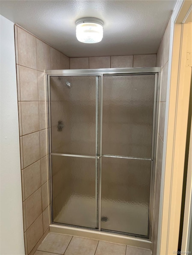 full bath featuring a stall shower, tile patterned floors, and a textured ceiling