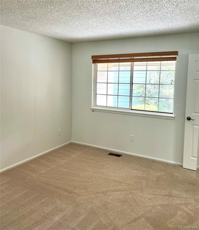 unfurnished room featuring carpet, a textured ceiling, healthy amount of natural light, and baseboards