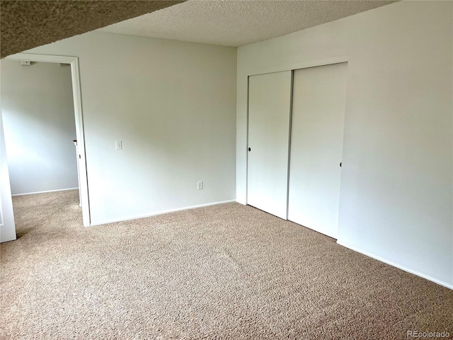 unfurnished bedroom featuring carpet flooring, a closet, baseboards, and a textured ceiling