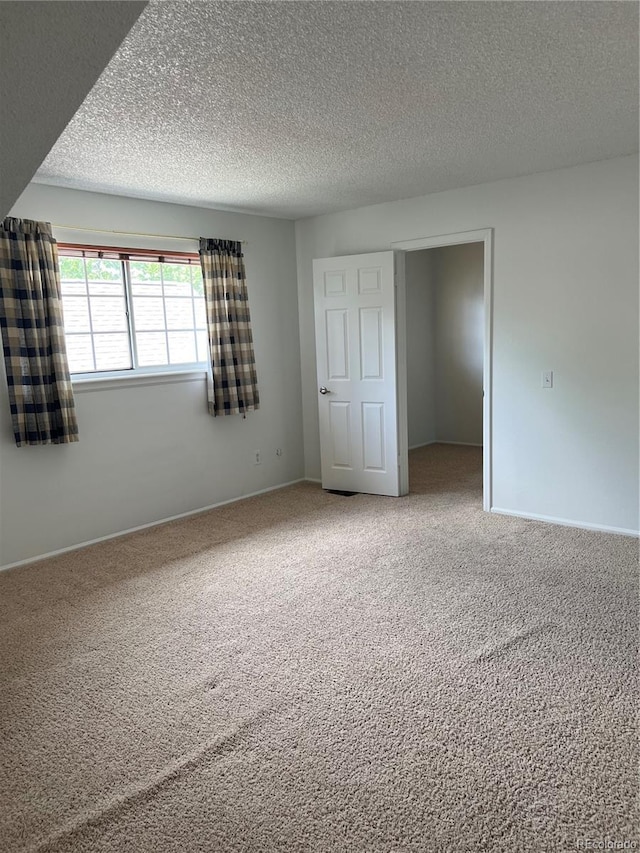 unfurnished bedroom featuring carpet flooring, a textured ceiling, and baseboards