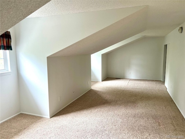 additional living space with carpet, vaulted ceiling, and a textured ceiling