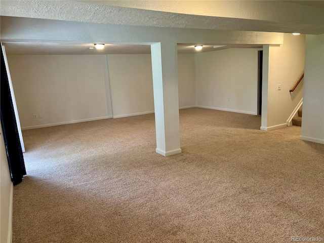 finished below grade area featuring carpet flooring, stairway, baseboards, and a textured ceiling