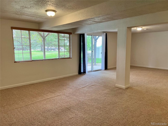 spare room with a textured ceiling, light carpet, and baseboards