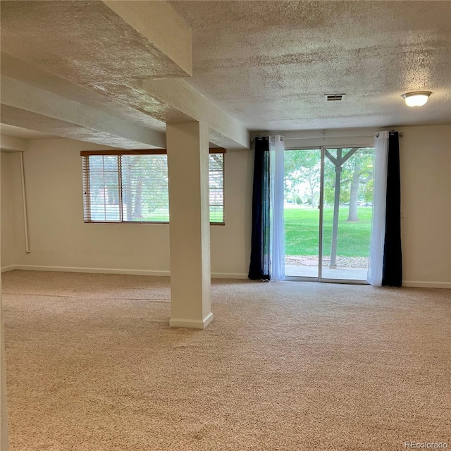 carpeted spare room featuring a textured ceiling, plenty of natural light, and baseboards