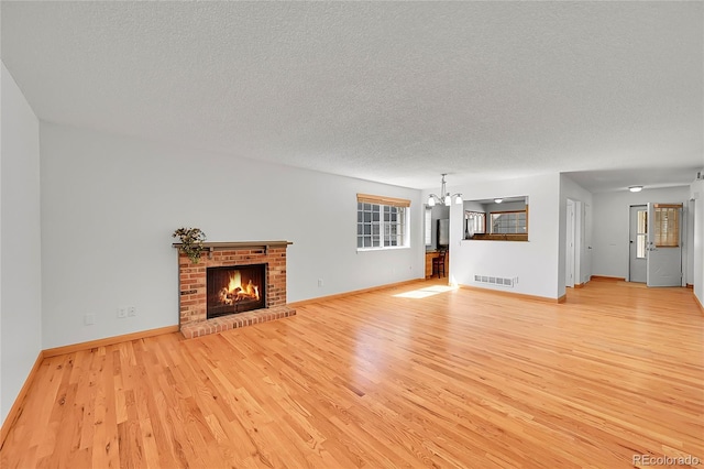 10369 E Red Mtn, Littleton, CO 80127 - unfurnished living room with a textured ceiling, light wood-style flooring, a chandelier, a fireplace, and baseboards