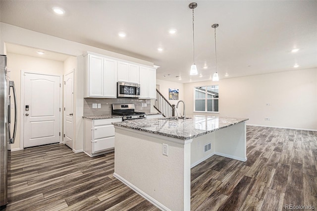 26267 E 3rd Ave, Aurora, CO 80018 - kitchen featuring appliances with stainless steel finishes, dark wood finished floors, white cabinetry, a kitchen island with sink, and recessed lighting