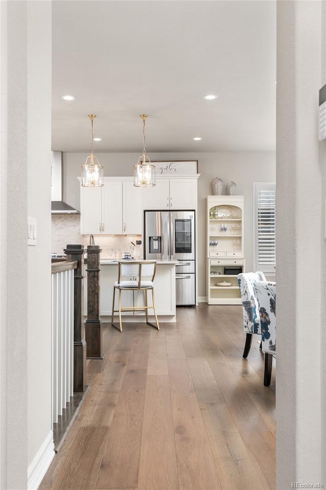 21972 E Allenspark Dr, Aurora, CO 80016 - kitchen with wall chimney range hood, dark wood-style flooring, white cabinetry, recessed lighting, and a kitchen breakfast bar