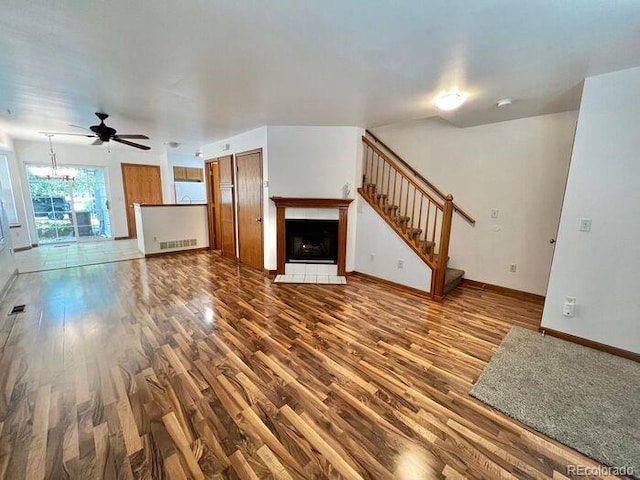 1115 W Swallow Rd Unit 20, Fort Collins, CO 80526 - unfurnished living room with wood finished floors, a tile fireplace, stairs, ceiling fan, and a chandelier