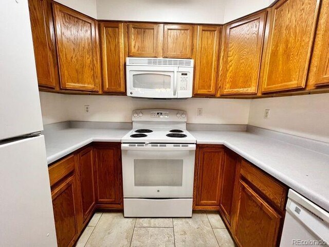 1115 W Swallow Rd Unit 20, Fort Collins, CO 80526 - kitchen with white appliances, brown cabinets, and light countertops